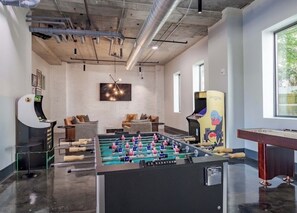 A modern indoor space with a foosball table, seating area, and a foosball table with a colorful design. - The Buckhead Suite (Atlanta)