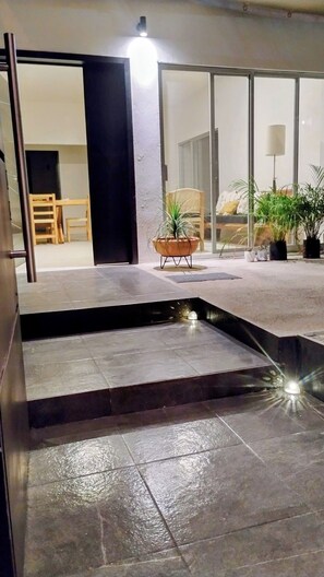 A modern interior with a stone floor, a small water feature, and a seating area with a chair and potted plants. - Family House in Huatulco, 4 Bedrooms, pool, A.A. Wi Fi, centrally located parking (bahias de huatulco)