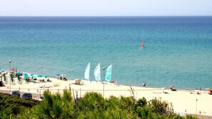 A beach with umbrellas, chairs, and sailboats. - Spacious Beach Apartment for 6 (Badesi)