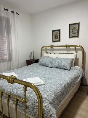 A room with a bed, a nightstand, a lamp, and two framed pictures on the wall.