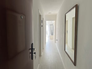 A hallway with a door, a key, and a mirror on the wall.