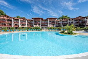 Ein Hotel mit großem Pool, mehreren Balkonen und blauem Himmel.