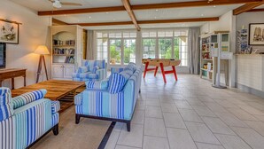 Ein geräumiger Wohnbereich mit gestreiften Sofas, einem Holztisch und einem Deckenventilator.