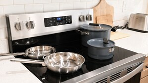 Une cuisine équipée d’une cuisinière en acier inoxydable, de deux casseroles et d’un grille-pain.