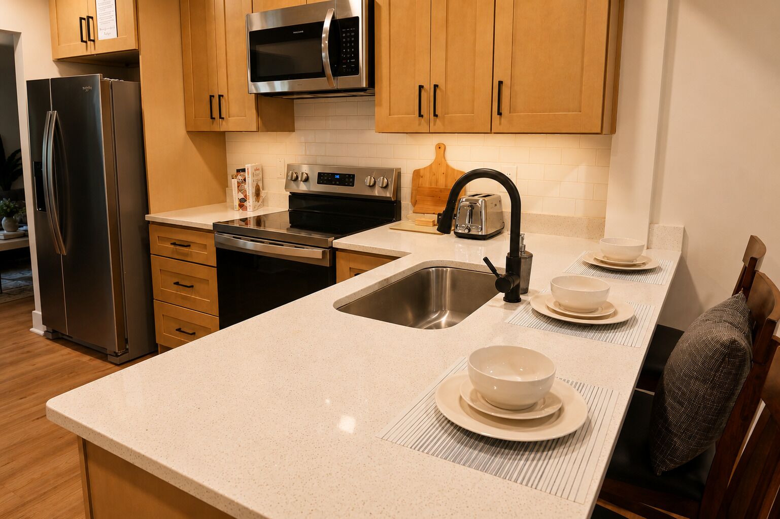 A kitchen with stainless steel appliances, wooden cabinets, a microwave, and a sink with a faucet.