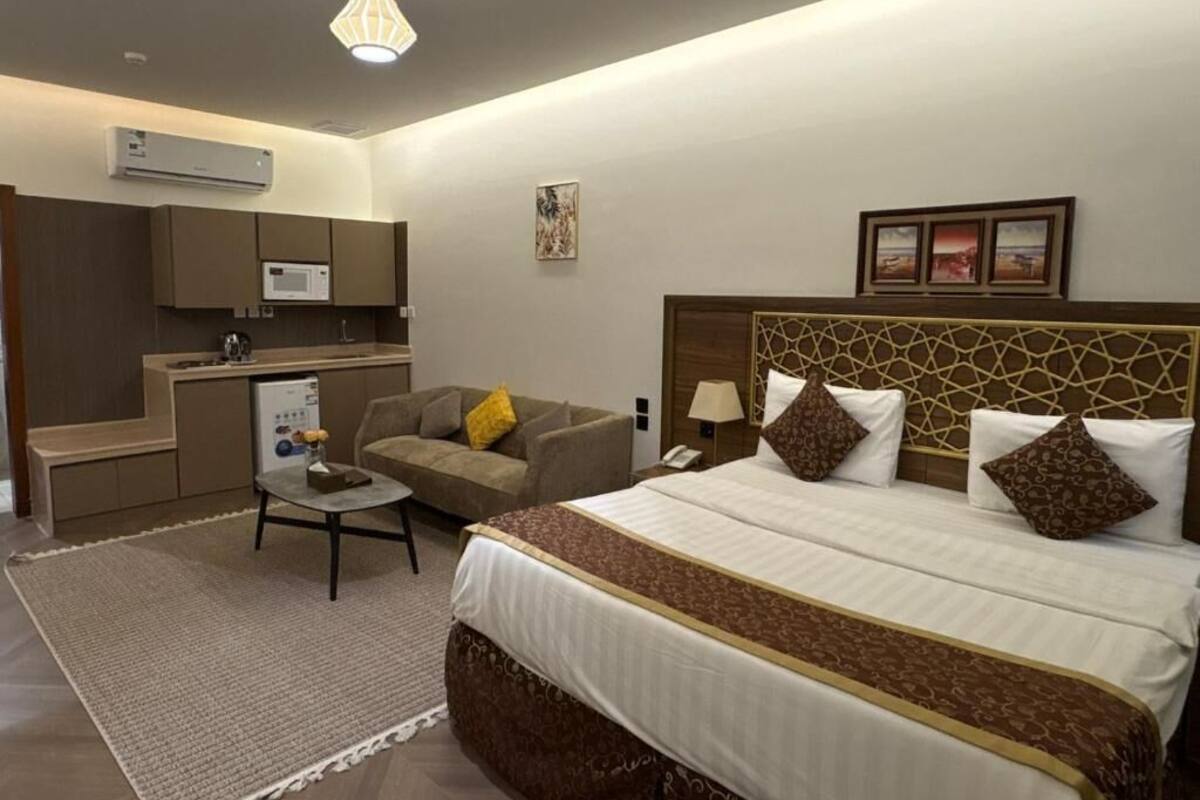Une chambre d’hôtel comprenant un lit, un canapé, une petite table, un bureau et une kitchenette.