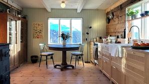 A kitchen with wooden cabinets, a stove, a dining table with chairs, and a window with a view of mountains.