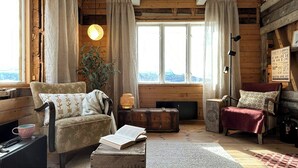 Een gezellig blokhut interieur met een groot raam, een open haard en een comfortabele zithoek.