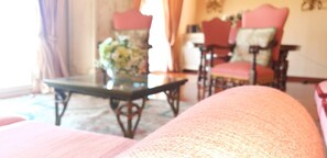 Ein Zimmer mit einer Couch, einem Tisch mit einer Vase und zwei Stühlen.