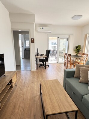 En moderne stue med et fjernsyn, et træ sofabord og en grå sofa.