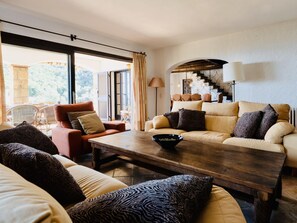 A living room with a sofa, armchair, and a coffee table. There is a staircase with a railing and a lamp. - La Torre CostaBravaSi - Pool, BBQ, sea views (Platja d'Aro)