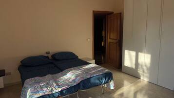 Quarto com cama, guarda-roupa e porta que dá para outro cômodo.
