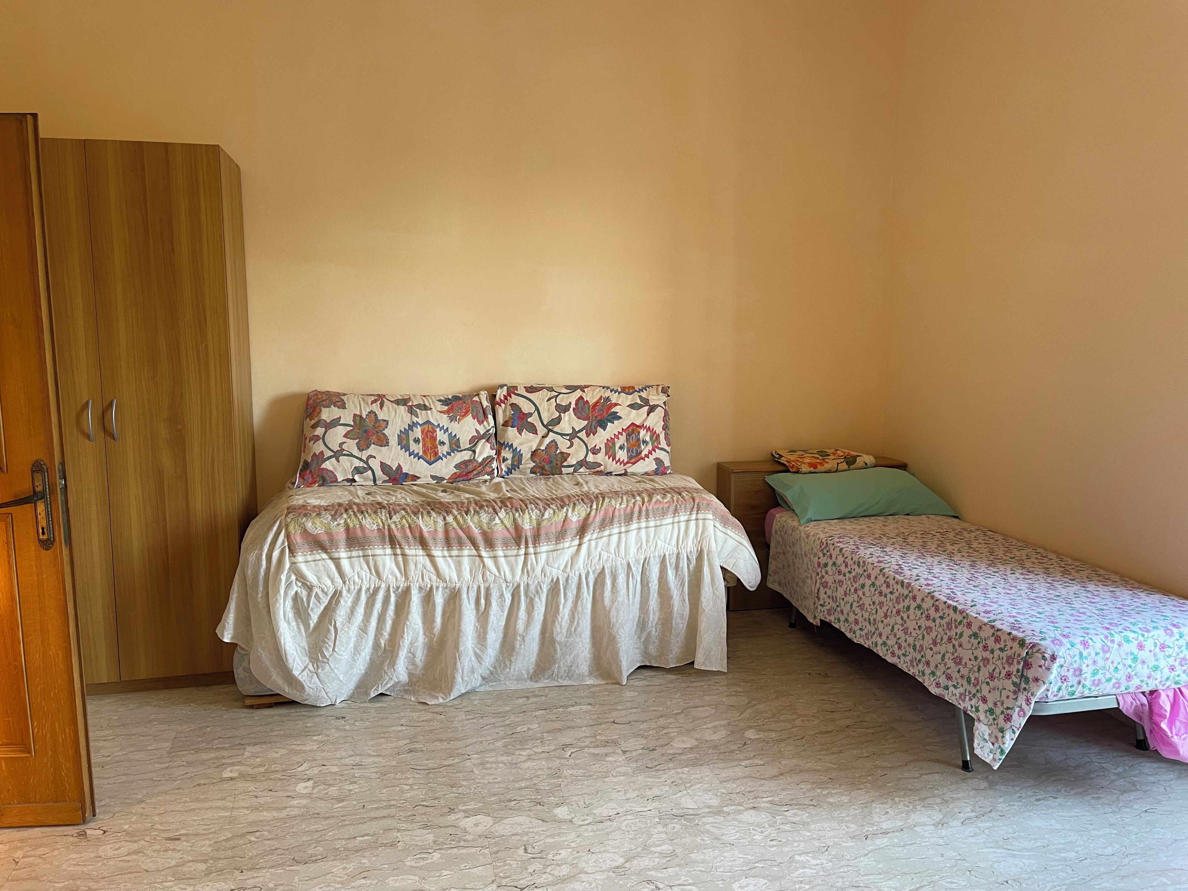 Una camera da letto con un letto matrimoniale, un letto singolo, un armadio e un comodino.