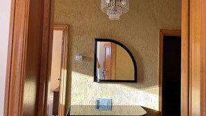 A bathroom with a wooden vanity, a mirror, and a chandelier.
