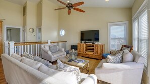 Ein Wohnzimmer mit Deckenventilator, Fernseher und zwei Sofas.