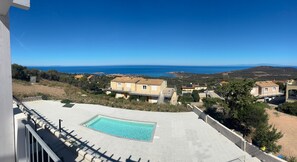 Un espace piscine offrant une vue dégagée sur la mer et les bâtiments environnants.