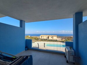 En balkon med udsigt til en swimmingpool og bygninger i det fjerne.