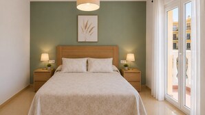 A bedroom with a large bed, two bedside tables with lamps, a wall-mounted artwork, and a view of a building through a window. - Apartment by Playa Serena & Golf Views (Roquetas de Mar)