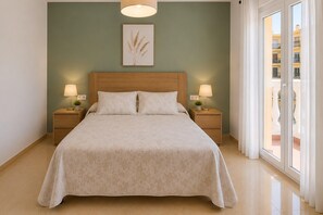 Ein Schlafzimmer mit einem großen Bett, zwei Nachttischen mit Lampen, einem Wandbild und Blick auf ein Gebäude durch ein Fenster.