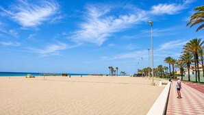 A beach with a paved walkway, palm trees, and a clear blue sky. - Apartment by Playa Serena & Golf Views (Roquetas de Mar)