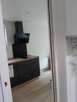 Una cocina con extractor negro, encimera de madera y salpicadero de azulejos blancos.