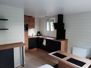 Una cocina moderna con una isla central, horno empotrado y una ventana que proporciona luz natural.