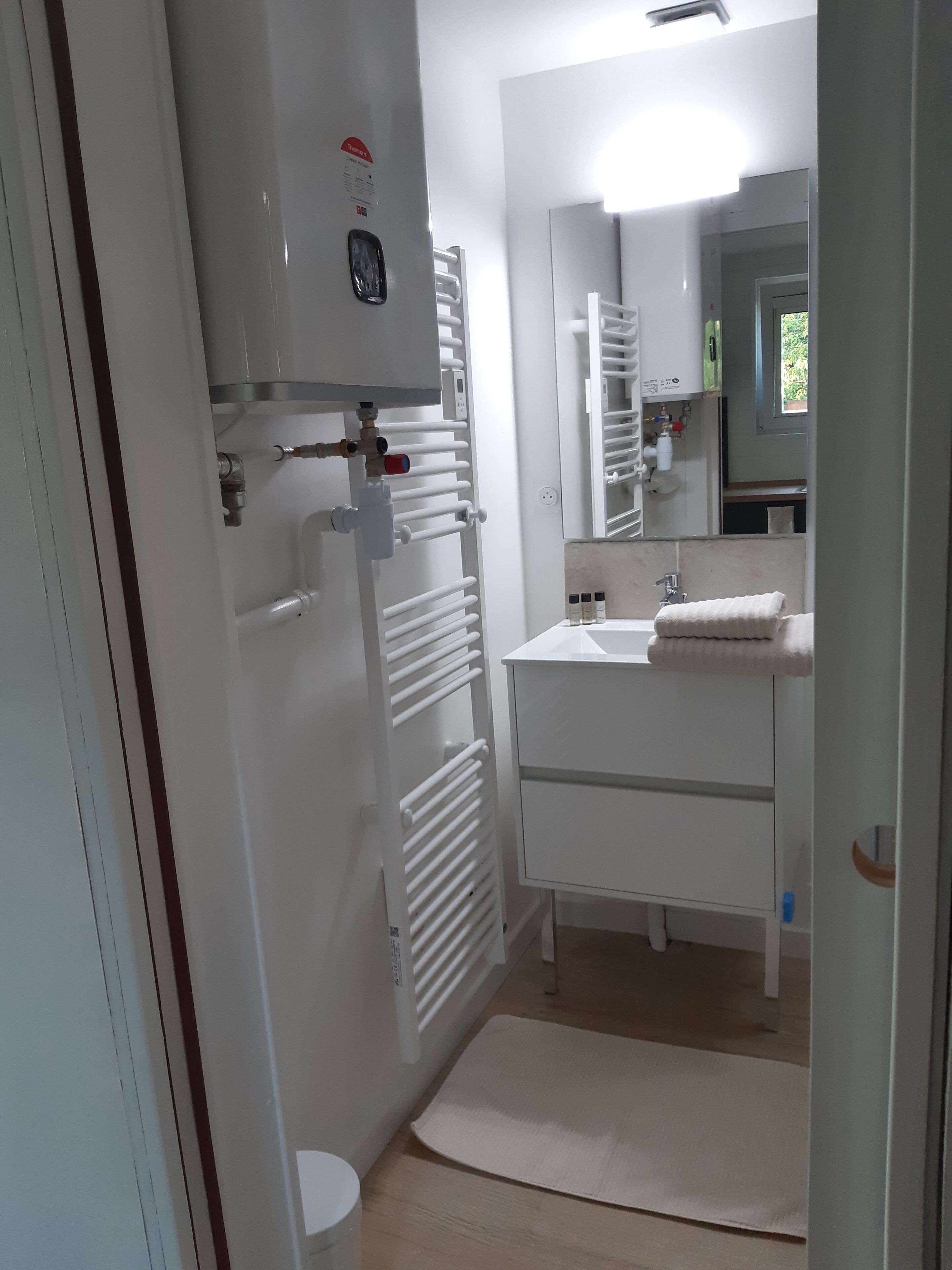 A bathroom with a white sink, mirror, towel rack, and a radiator.