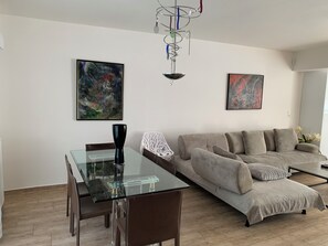 Ein modernes Wohnzimmer mit einem Glastisch, einer Couch und abstrakten Gemälden an den Wänden.