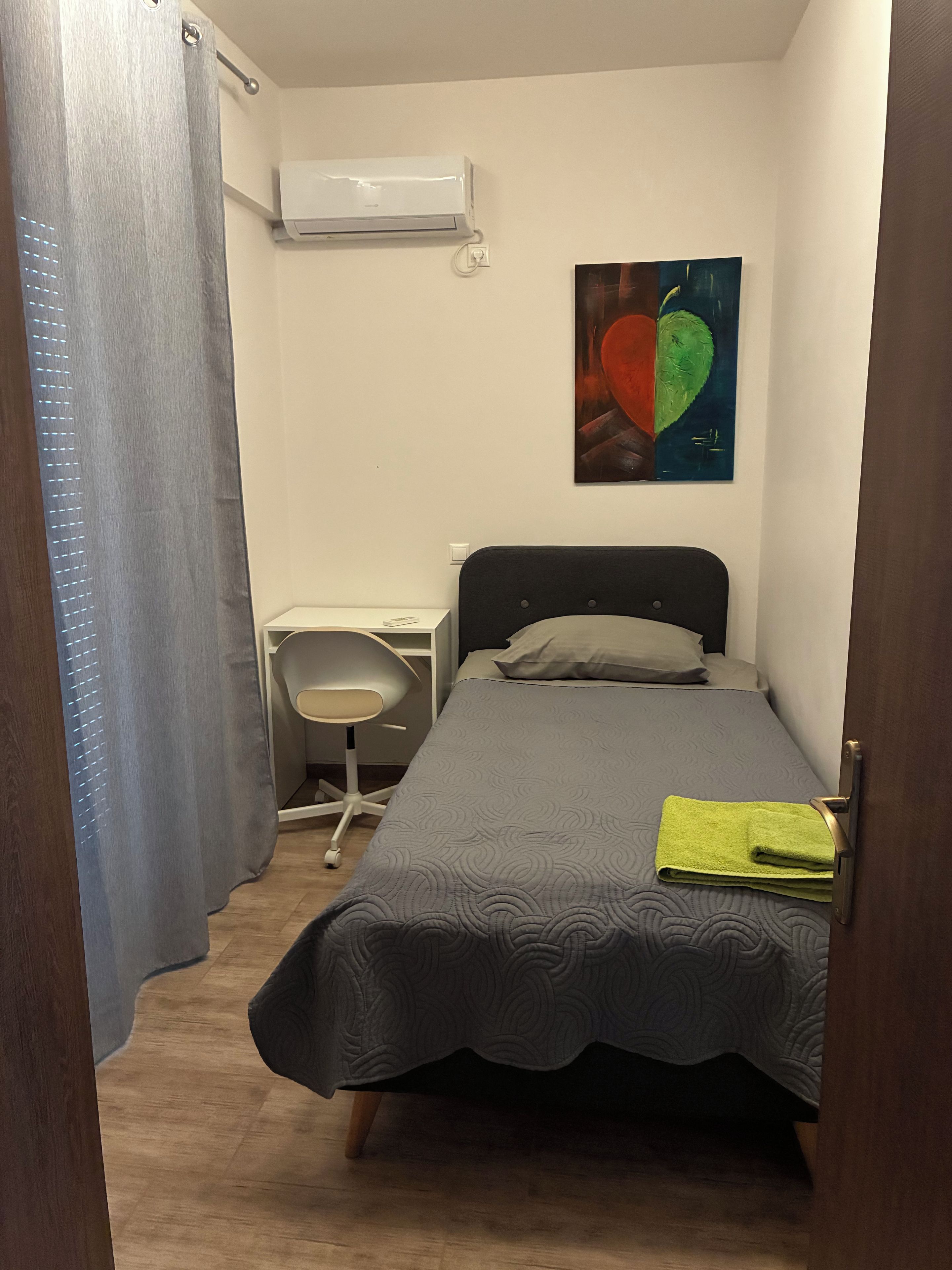 Quarto com cama, escrivaninha e ar condicionado.