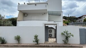 Un edificio moderno con techo plano, una entrada pequeña y dos unidades de aire acondicionado.