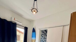 A bedroom with a bed, a ceiling fan, a surfboard decoration, and a view of the outside. - Your Home in Ubatuba - Comfort Near the Beach! (Ubatuba)