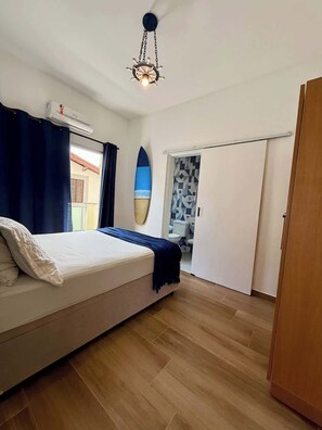 Een slaapkamer met een bed, een plafondventilator, een surfboard decoratie en uitzicht op buiten.