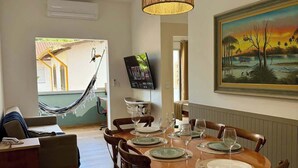 A dining area with a round wooden table set for six, surrounded by wicker chairs. - Your Home in Ubatuba - Comfort Near the Beach! (Ubatuba)