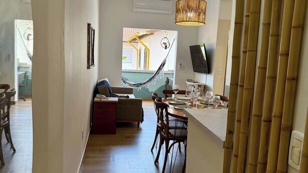 A modern kitchen with a dining area, a hammock, and a view of the outside. - Your Home in Ubatuba - Comfort Near the Beach! (Ubatuba)