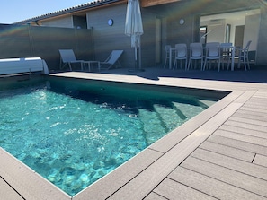 Una piscina rectangular con una cubierta de madera alrededor.