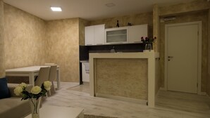 Cozinha moderna com armários brancos, ilha central e área de jantar com mesa e cadeiras.