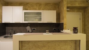 Cozinha com armários brancos, painel de parede preto e bancada com um pote de vidro e uma garrafa.