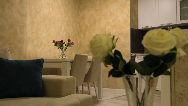 Uma sala de estar com um sofá, uma mesa de centro e um vaso com flores.
