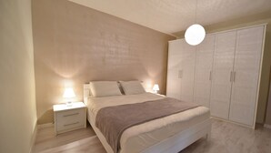 Quarto com cama, mesa de cabeceira, luminária, guarda-roupa e luminária pendente.