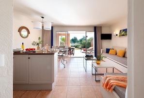 A modern kitchen with a central island, dining area with a table and chairs, a sofa with cushions, and a TV mounted on the wall. - Aesthetic Coastal Family Escape (Roquebrune-sur-Argens)