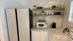 Une cuisine moderne équipée d’un four à micro-ondes encastré, d’une machine à café et d’un évier.