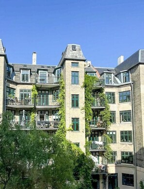 Un edificio de varios pisos con balcones, ventanas amplias y fachada de piedra.
