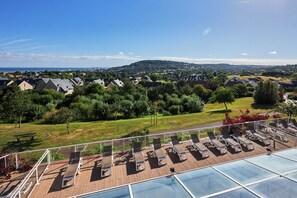 A rooftop with sun loungers and a pool, overlooking a residential area with houses and greenery. - Luxe Normandy Duplex for 8 With Pool (Houlgate)
