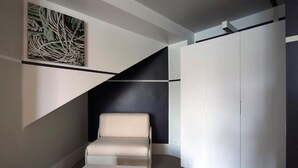 Une pièce moderne avec une chaise blanche, un mur d’accent noir et un grand tableau abstrait.