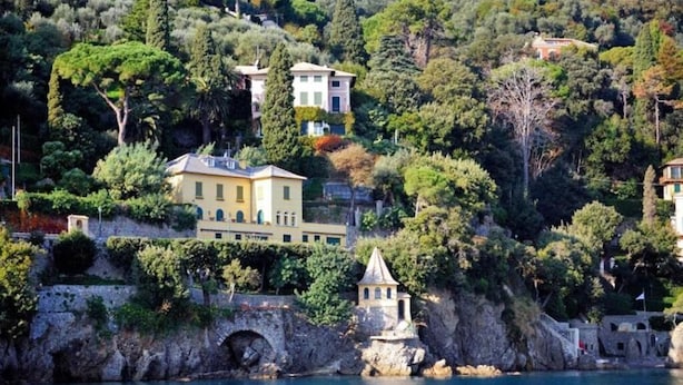 Une propriété située sur la côte, comprenant une grande maison, une petite structure en forme de tour et un pont en pierre.