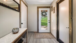 A hallway with a wooden bench, a door with a view of greenery, and a mirror on the wall. - Harrisonburg 3 bedroom and HOT TUB! Minutes from Downtown NEW! (Harrisonburg)
