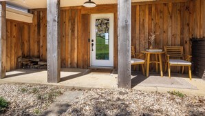 A wooden porch with a door, a table, and two chairs. - Harrisonburg 3 bedroom and HOT TUB! Minutes from Downtown NEW! (Harrisonburg)