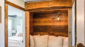 A cozy room with a wooden bench, a white bed, and a ceiling light fixture. - Harrisonburg 3 bedroom and HOT TUB! Minutes from Downtown NEW! (Harrisonburg)