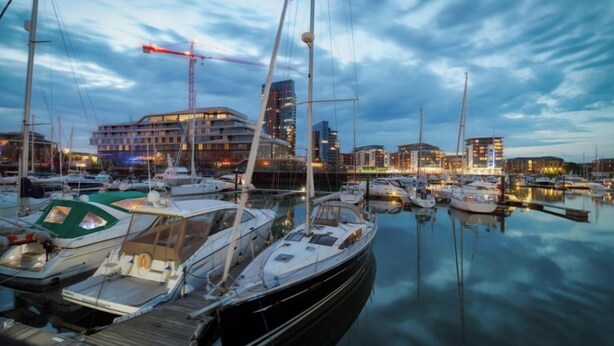 A marina with multiple boats docked, a building with a crane, and a city skyline in the background. - Southampton - House - Sleeps 6 - Near Airport (Southampton)