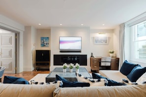 Ein Wohnzimmer mit Flachbildfernseher, Kamin, Sofa, Couchtisch und Schrank.